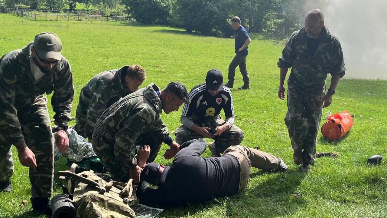 Aaron Ramsey, Willy Caballero and other coaches tending a casualty in a military training exercise
