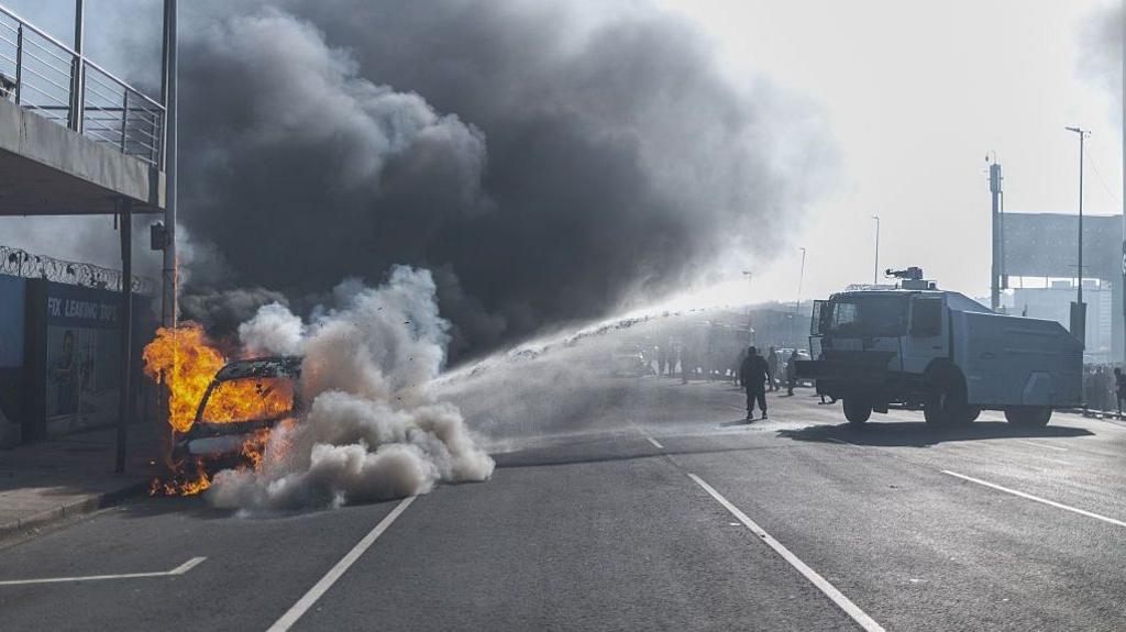 Vehicle on fire with police water‑cannon