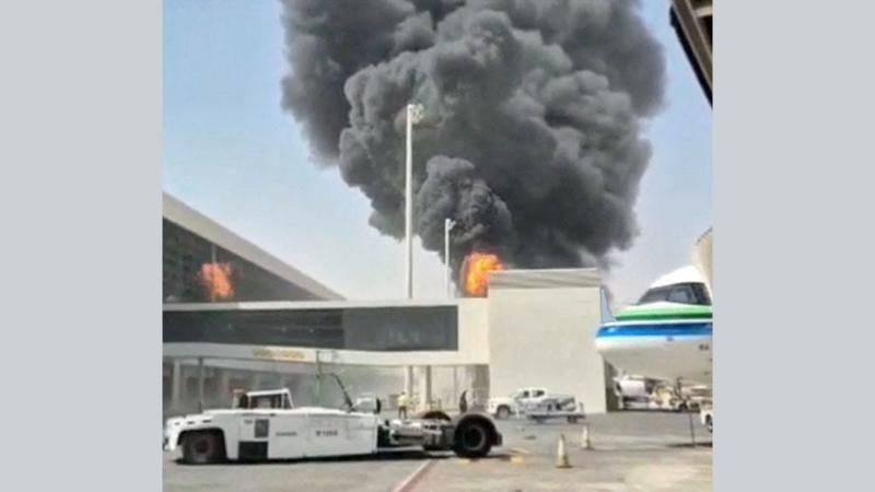 Large flames burn beside airport terminal buildings as thick black smoke billows into the sky
