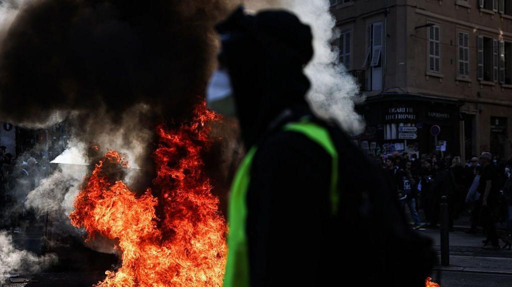 A protester passes a fire during unrest in Marseille, 17 October