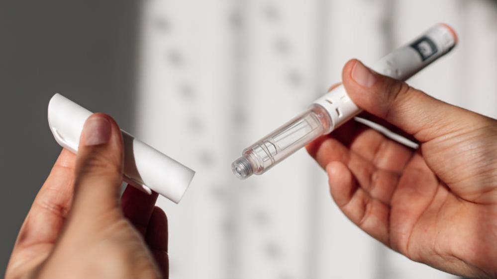 A woman’s hands hold a weight loss injection pen