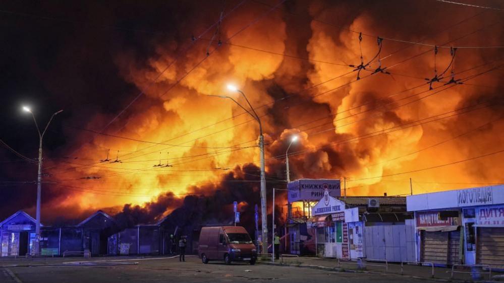 Firefighters work at the site of a market hit by a Russian missile strike in Kyiv
