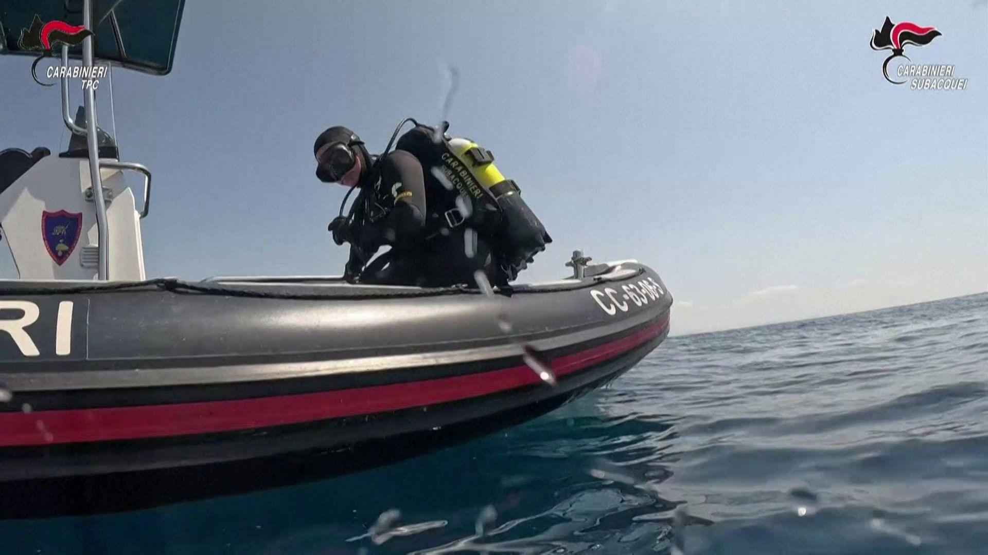 Divers observe the ancient Roman ship wreck at the bottom of the sea off Sicily