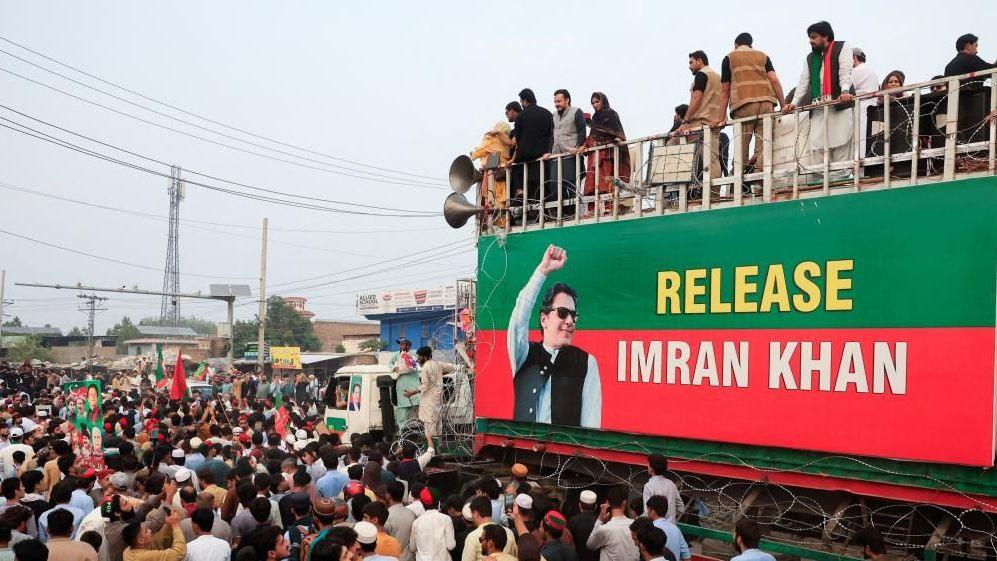 Thousands of supporters in front of a banner of Imran Khan