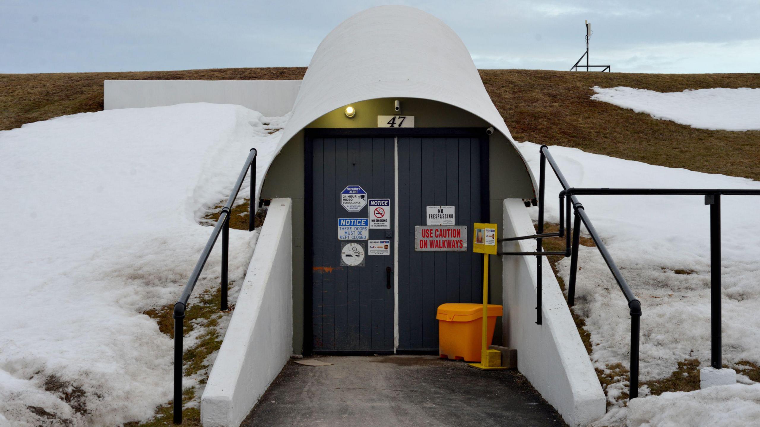 Two black doors with warning signs built into a snow covered hill