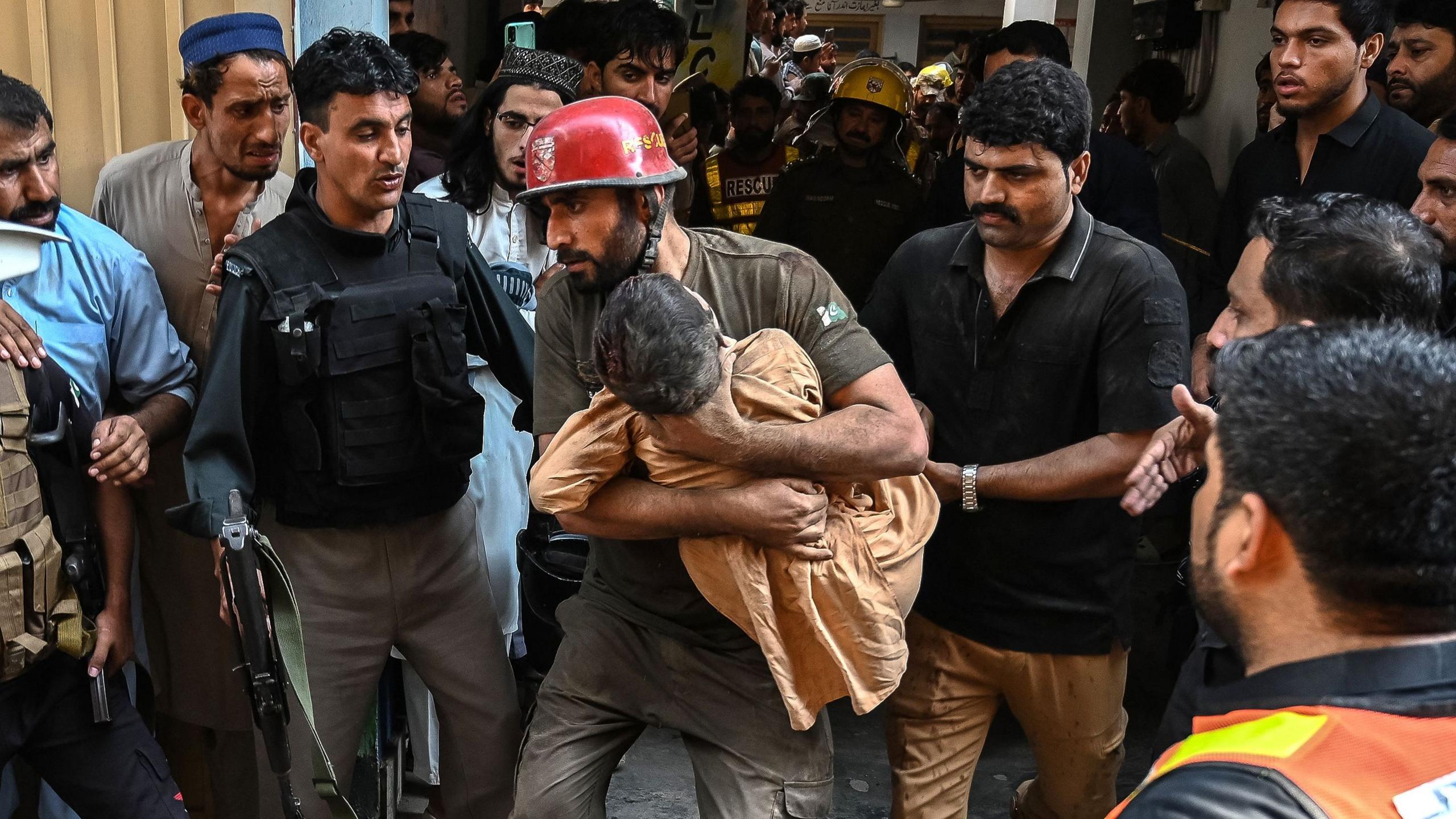 Rescue worker carrying a child near collapsed school building